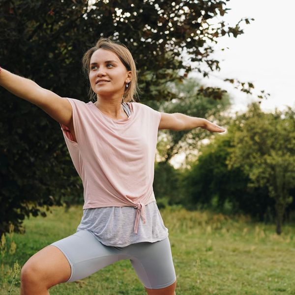 Smiling woman stretching gently outdoors in a park.